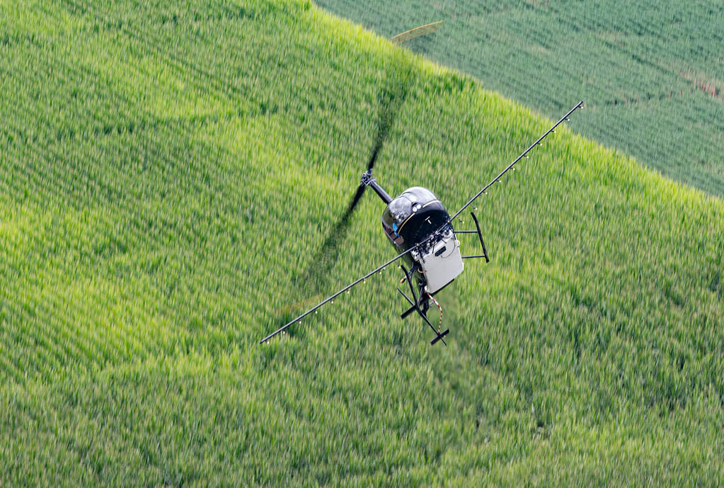 A helicopter is flying over a field of tall grass. AI generated content
