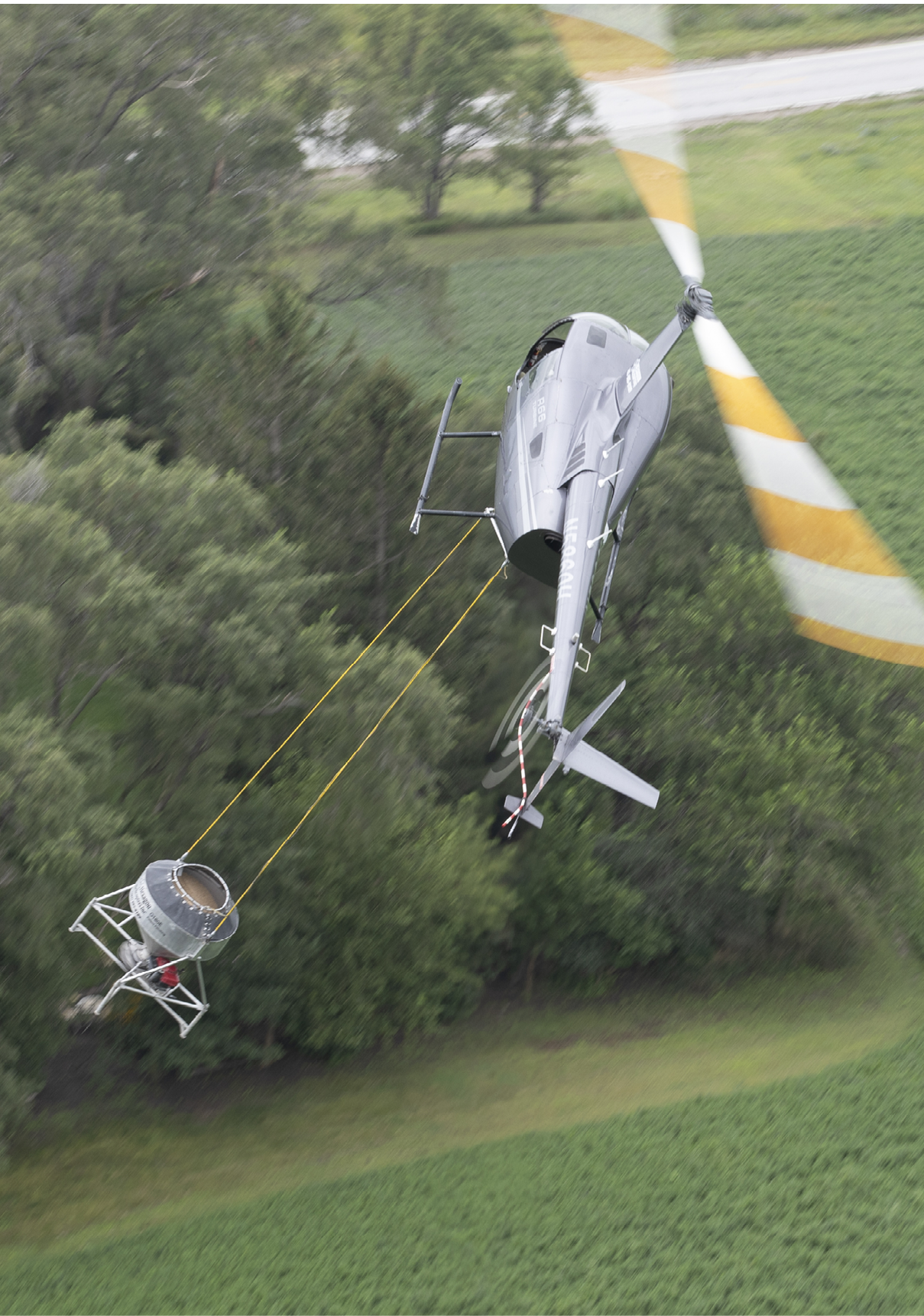 A helicopter is flying over a field with a person in a basket attached to it. AI generated content