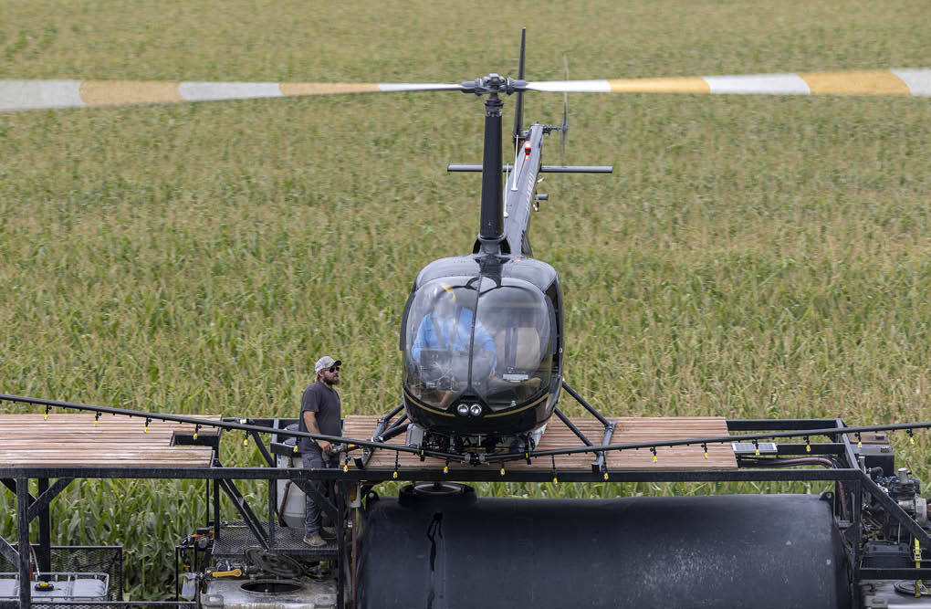 A man is standing on a helicopter in a field. AI generated content