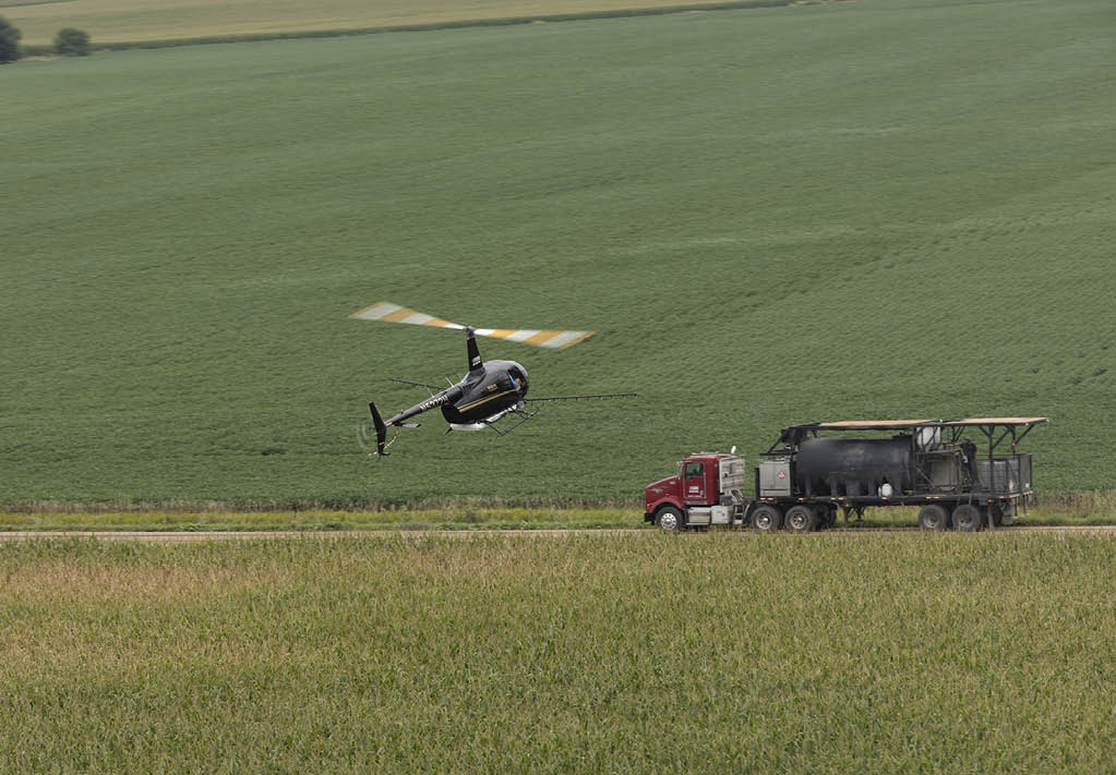 A helicopter is flying over a field with a truck nearby. AI generated content