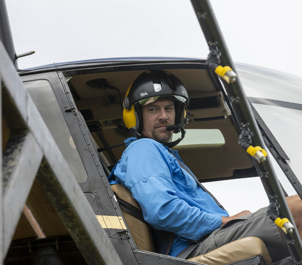 A man wearing a helmet is sitting in a cockpit of a helicopter. AI generated content