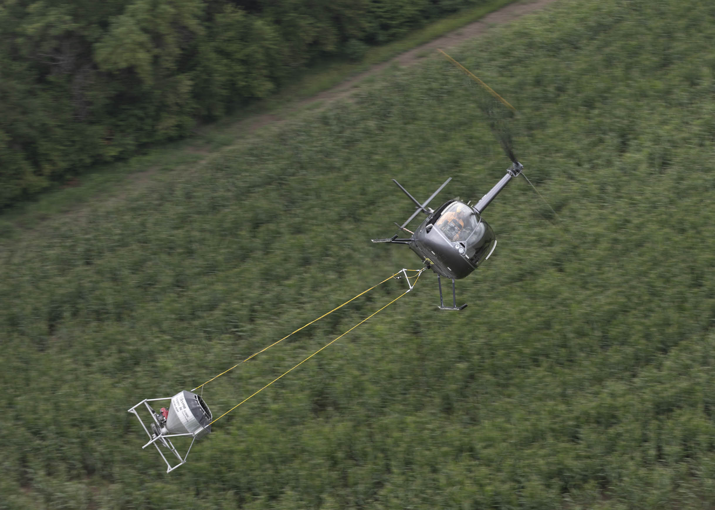 A helicopter is flying over a field with a person hanging from it. AI generated content
