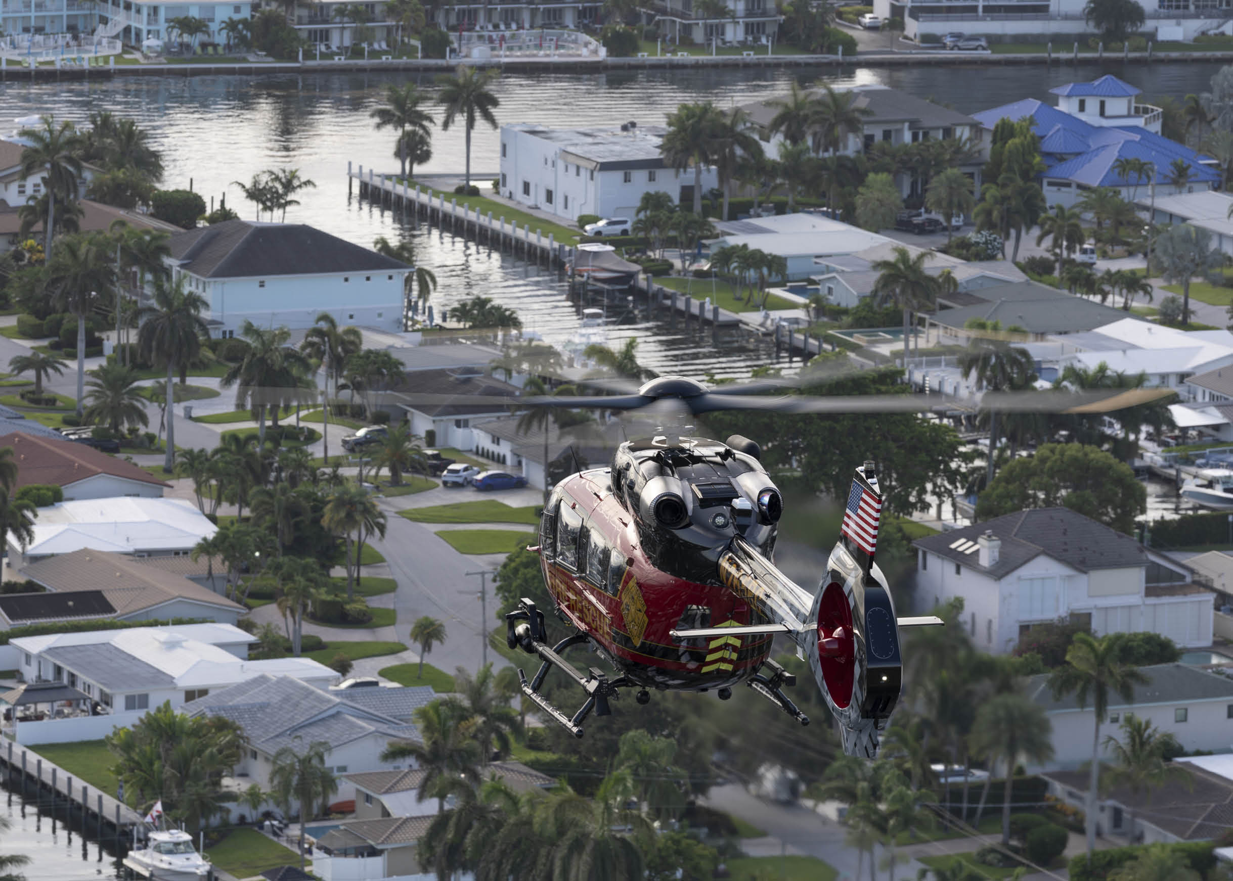 A red, white, and blue helicopter is flying over a neighborhood. AI generated content