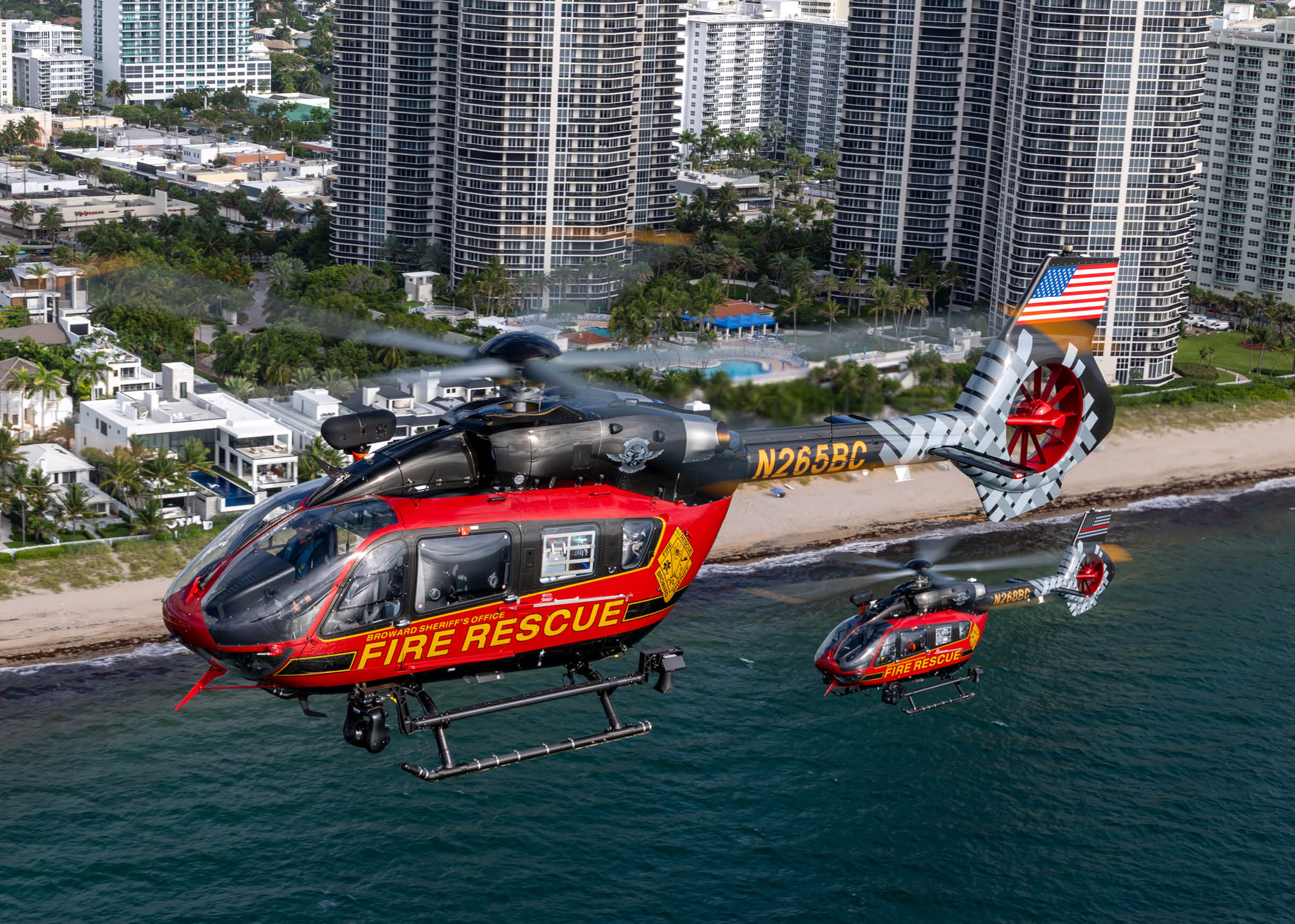 Two helicopters are flying over a beach, one is a fire rescue helicopter and the other is a smaller one. AI generated content