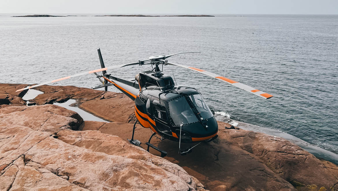 A helicopter is parked on a rocky surface near the water. AI generated content