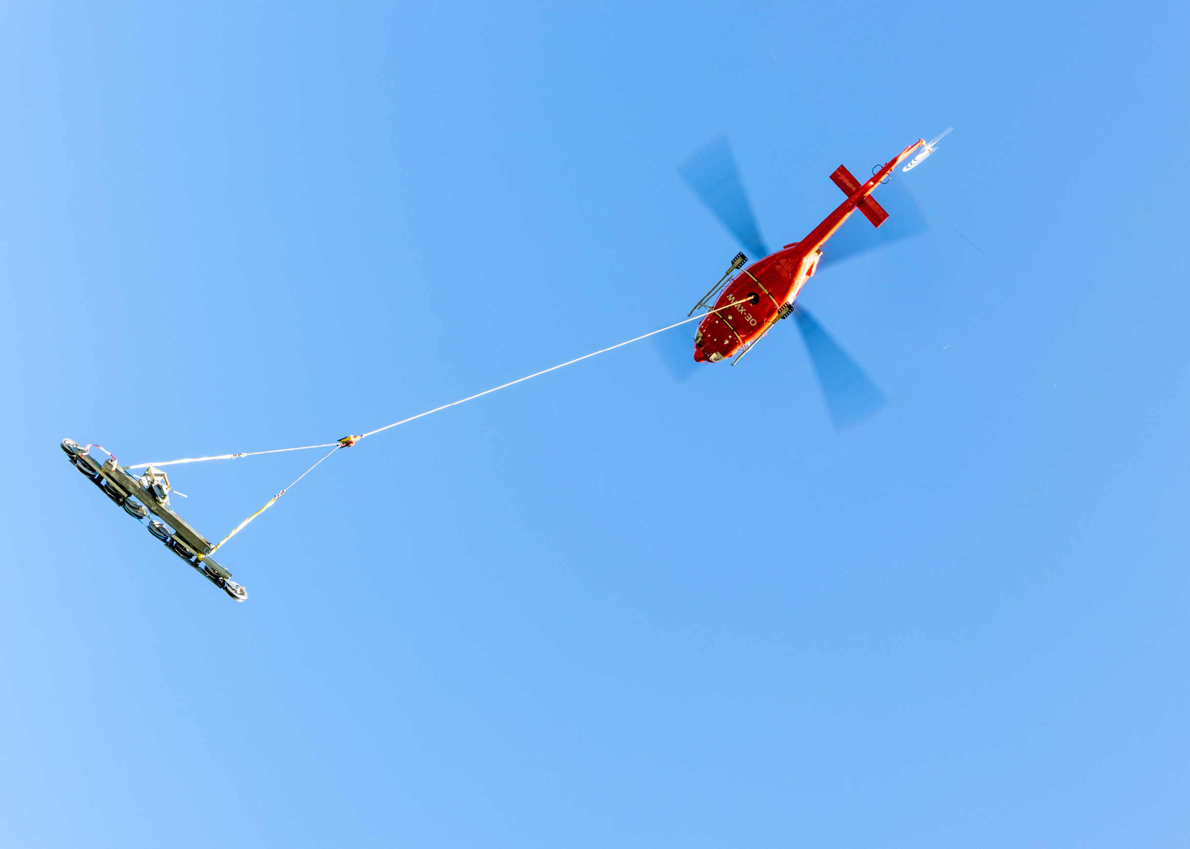 A red helicopter is flying in the sky with a rope attached to it. AI generated content