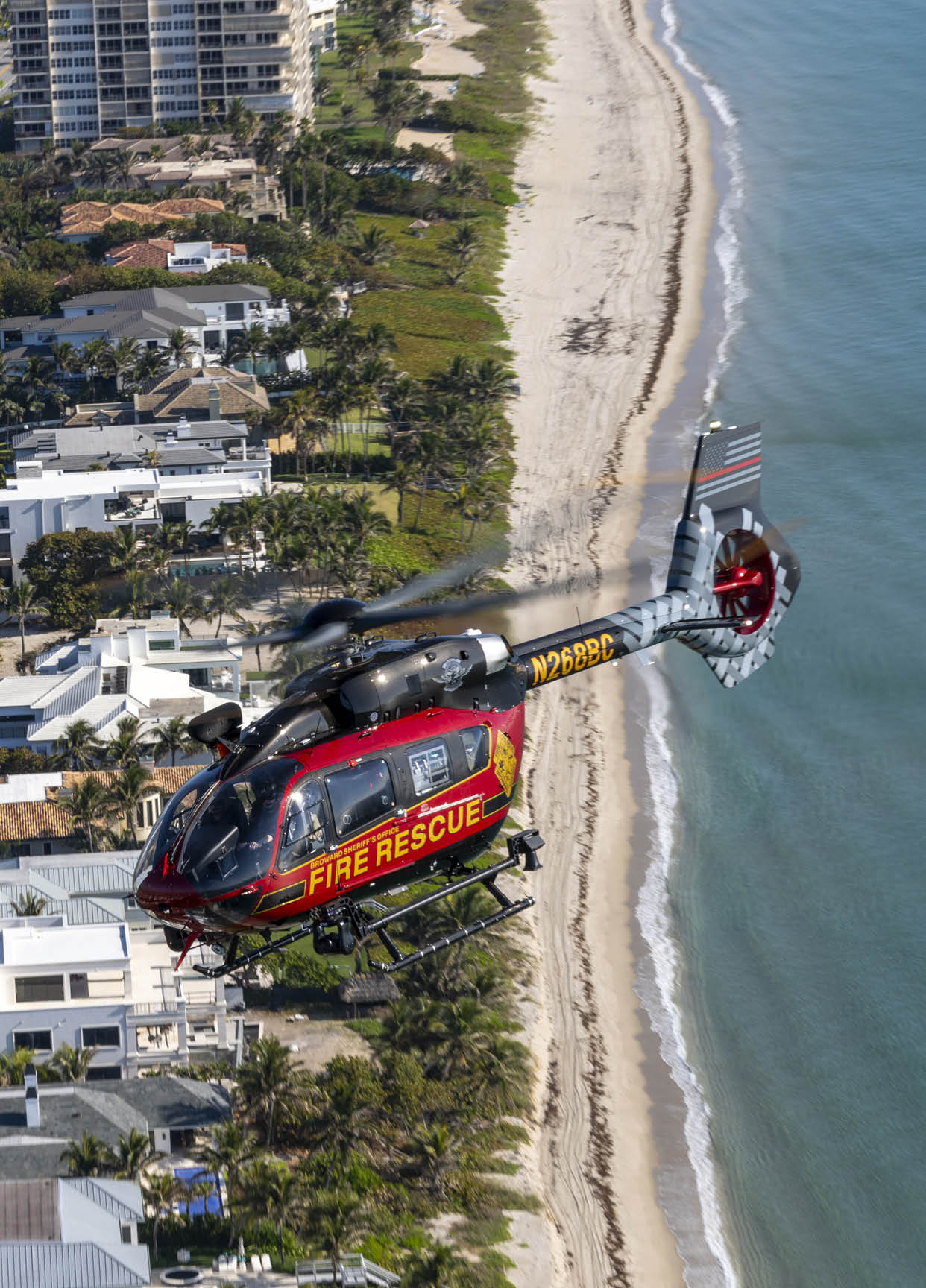 A red and yellow helicopter is flying over a beach. AI generated content
