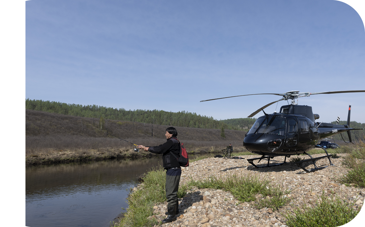 A man is standing on a rocky shore, holding a fishing pole, and looking at a helicopter. AI generated content