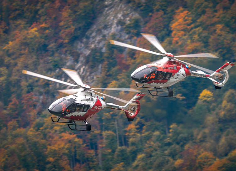 Two helicopters flying in the air, one is red and white and the other is red and black. AI generated content