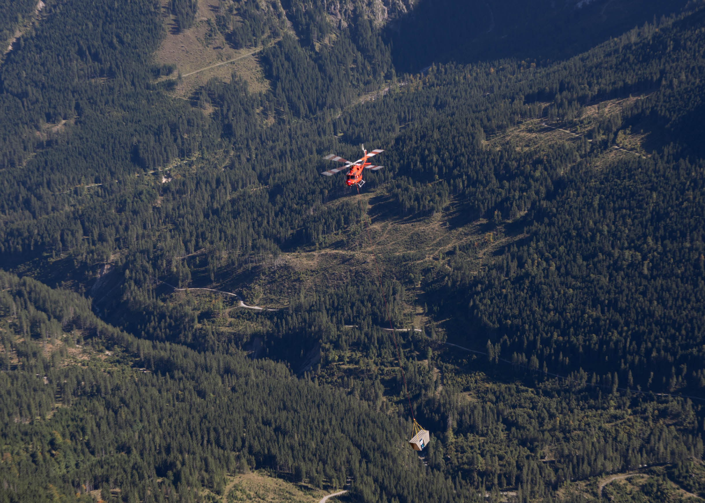 A red helicopter is flying over a forested mountain. AI generated content