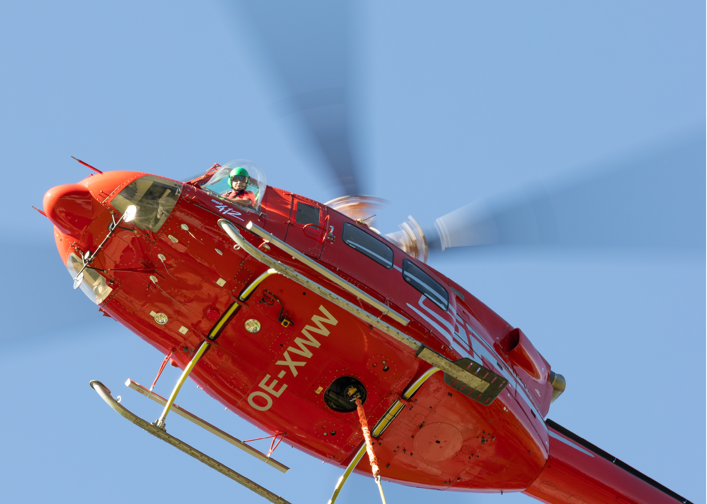 A red helicopter with a large propeller is flying in the sky. AI generated content