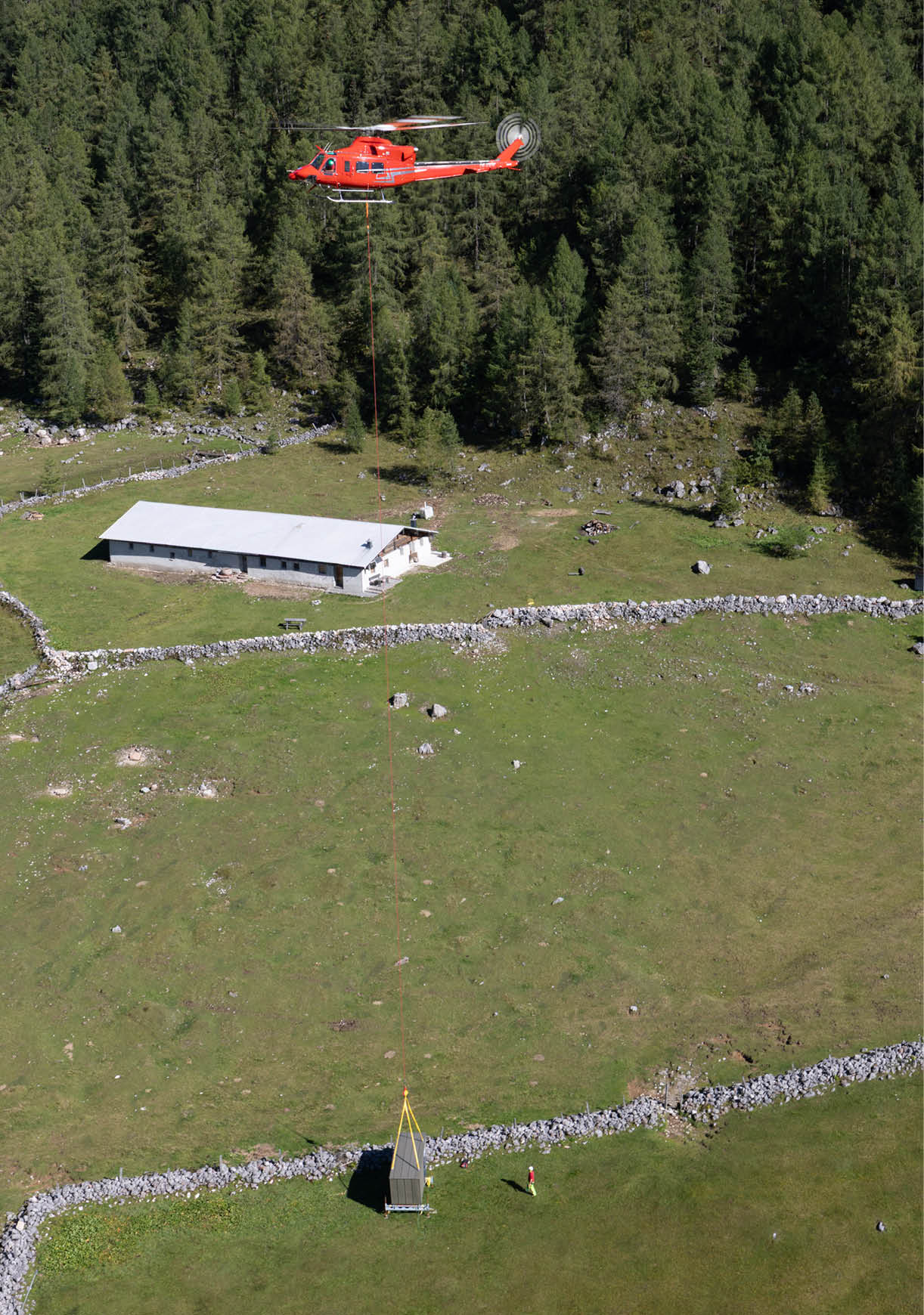 A red helicopter is flying over a field with a person standing in it. AI generated content