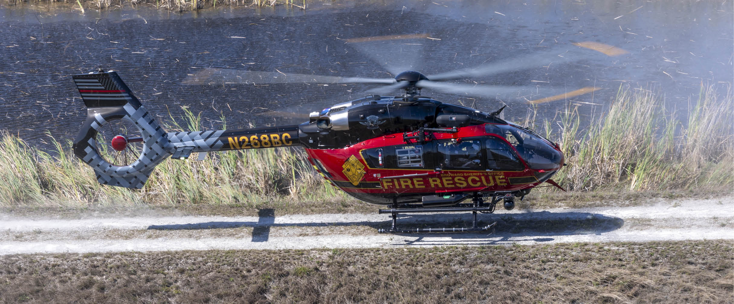 A red and yellow helicopter with the words “Fire Rescue" on the side is flying over a field. AI generated content