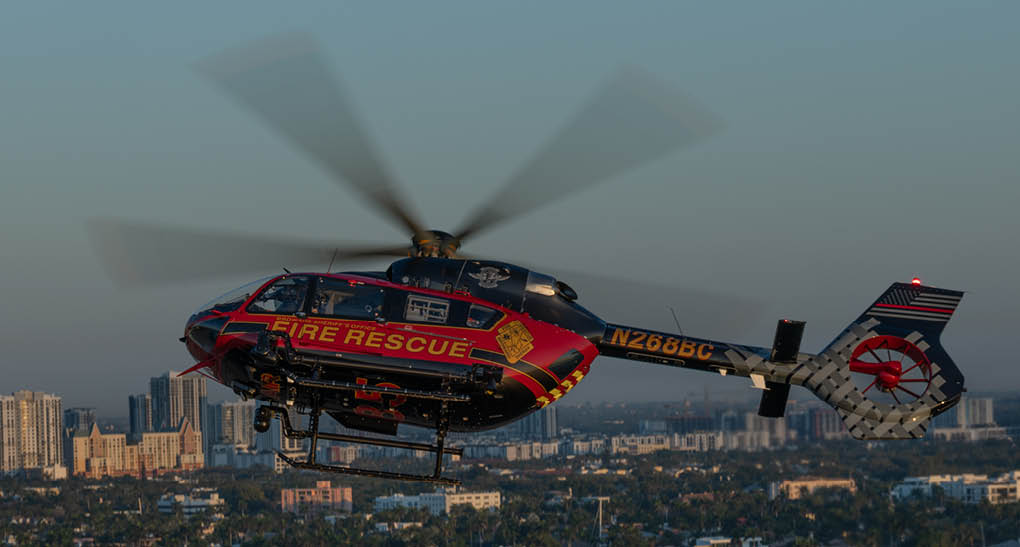 A red and yellow helicopter with the words “Fire Rescue" on the side is flying over a city. AI generated content