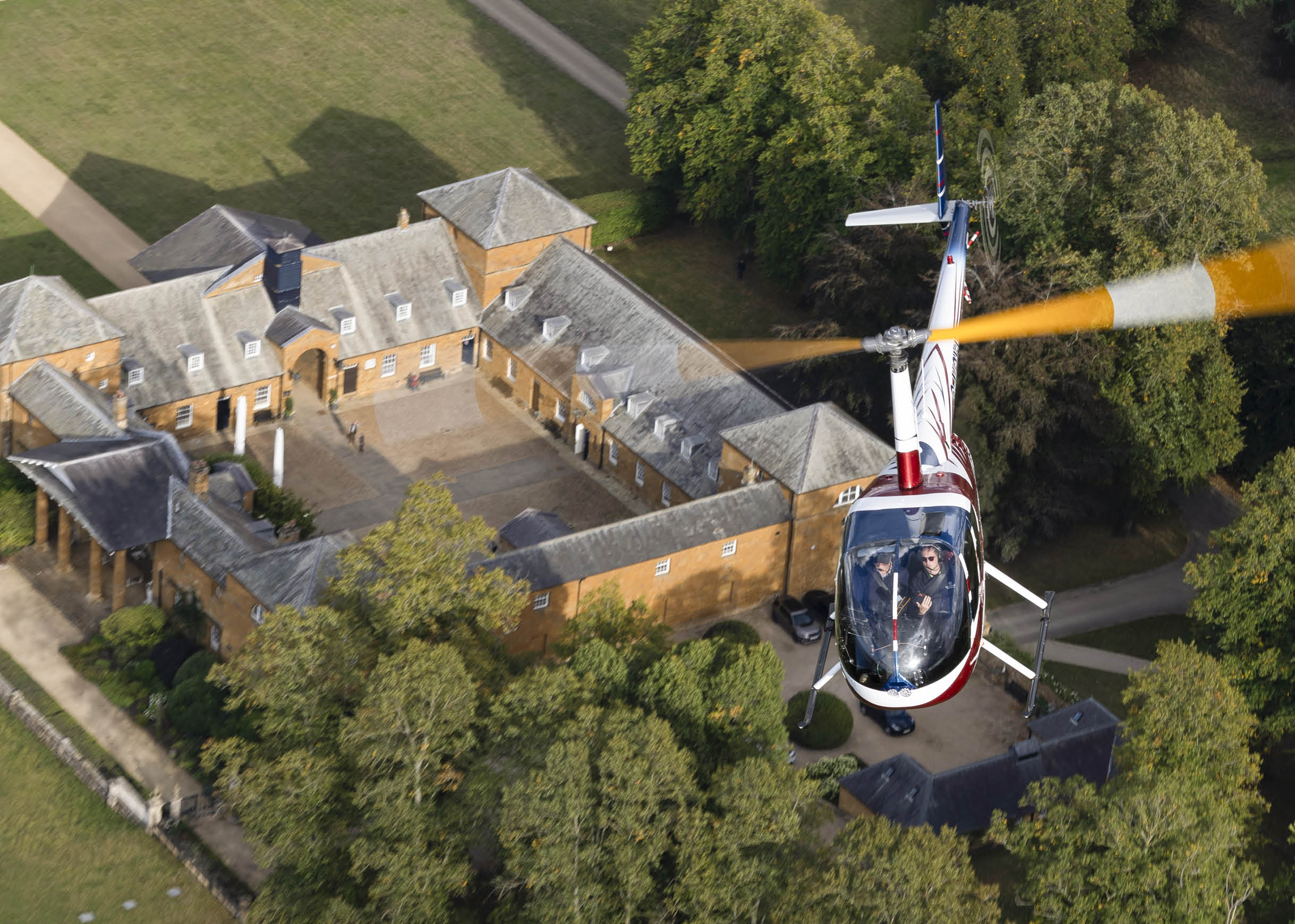A white helicopter is flying over a large house. AI generated content