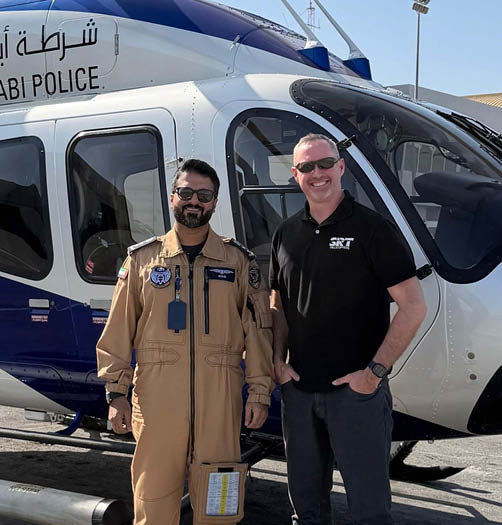 Two men standing next to a helicopter, one wearing a uniform. AI generated content