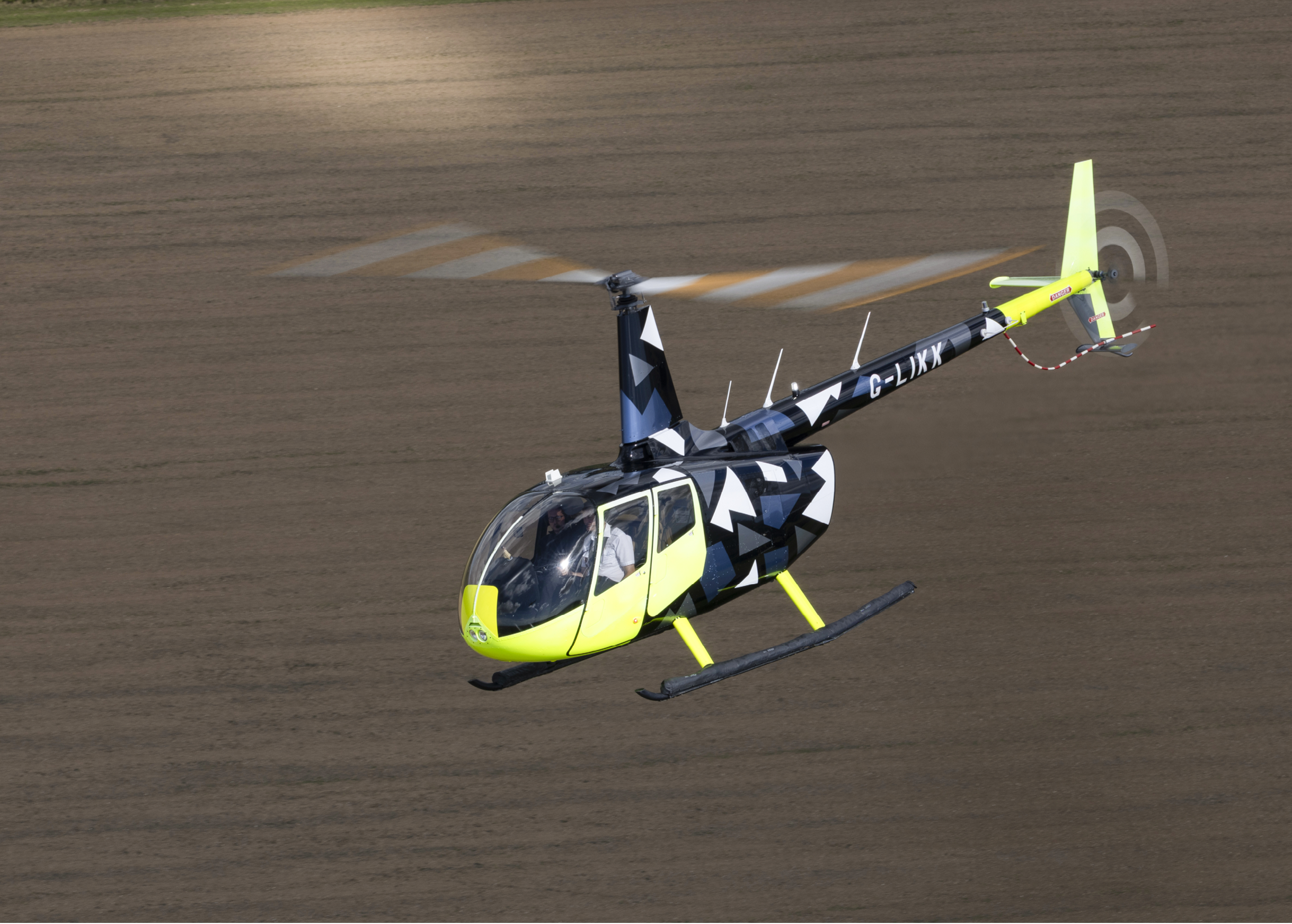 A yellow and black helicopter is flying in the air. AI generated content