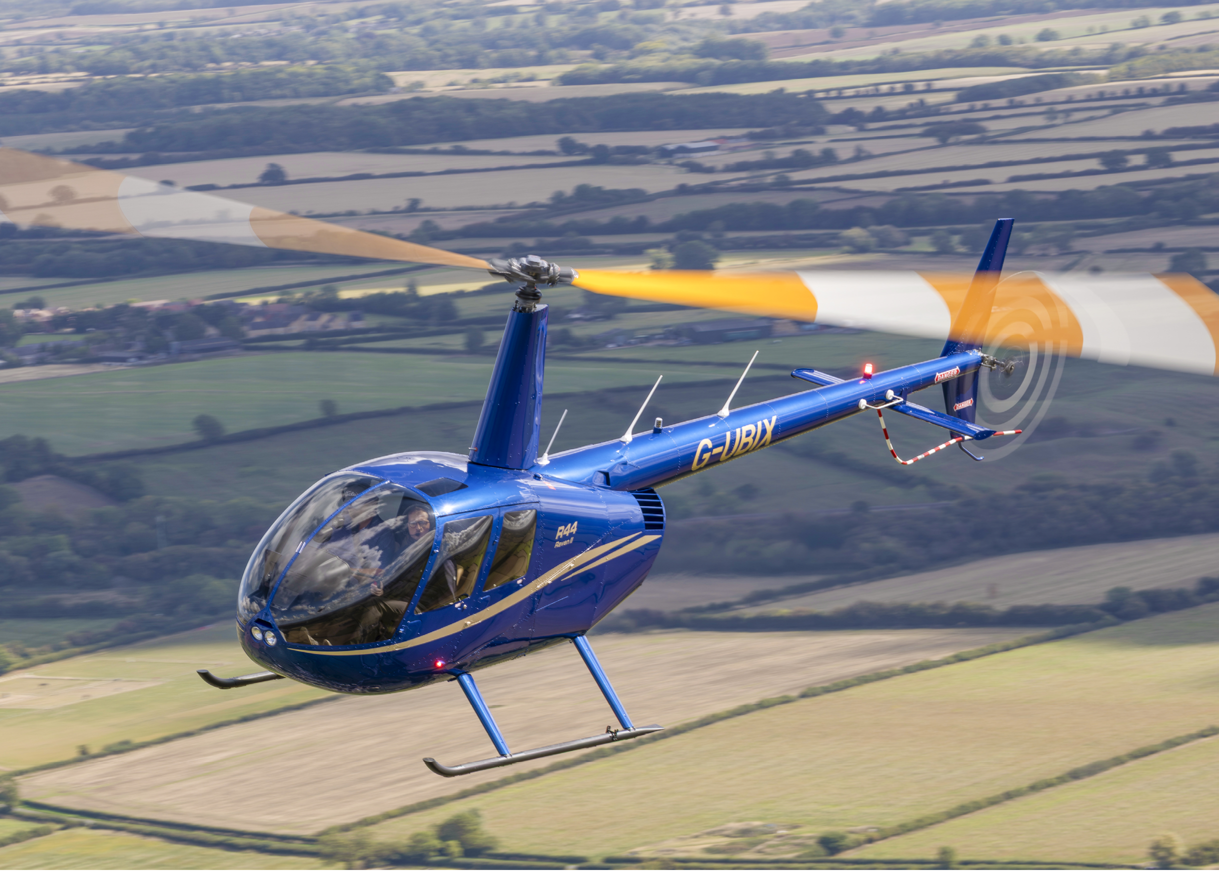 A blue helicopter is flying over a field with a yellow blade. AI generated content