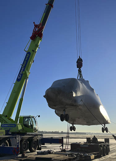 A crane is lifting a large object, possibly a plane, out of the snow. AI generated content