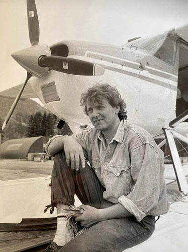 A man is sitting on the ground next to a small airplane. AI generated content