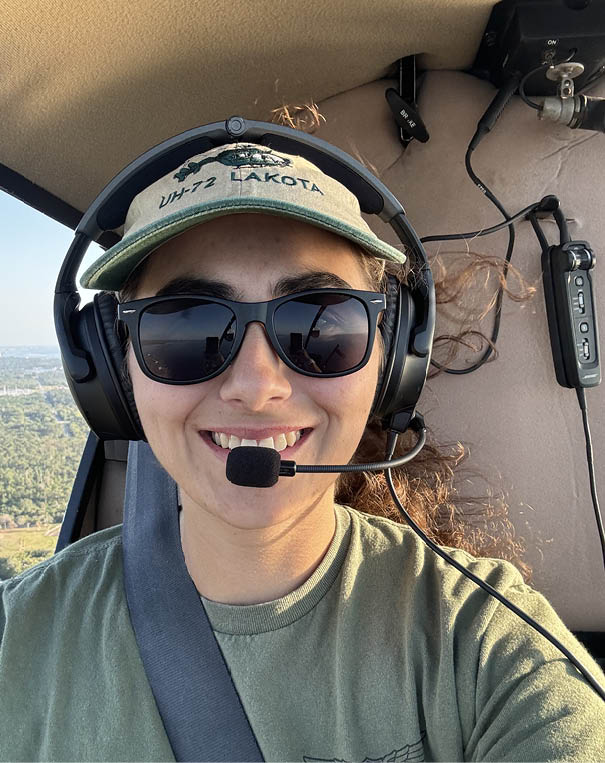 A woman wearing a green hat and sunglasses is smiling and holding a microphone. AI generated content