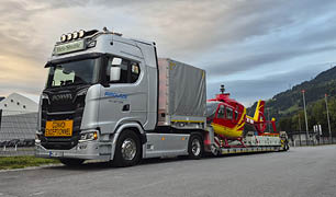 A semi truck is hauling a large helicopter on its trailer. AI generated content