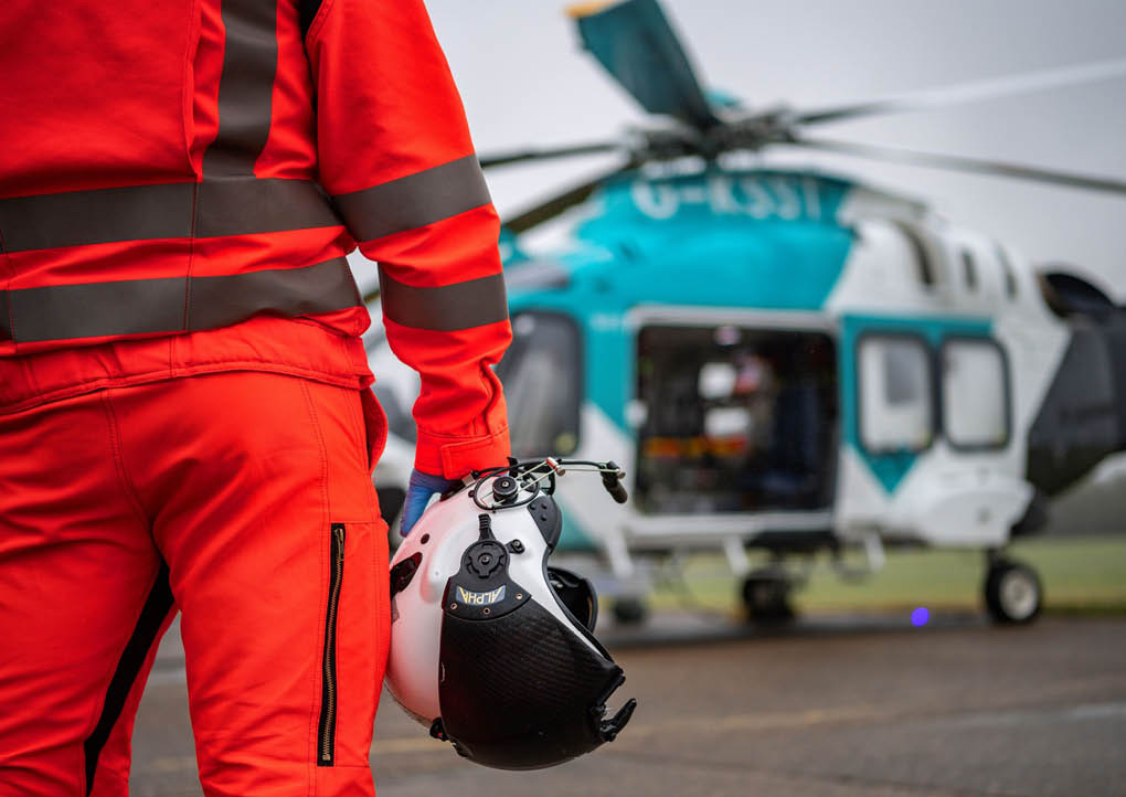 A man in an orange jumpsuit is standing next to a helicopter. AI generated content