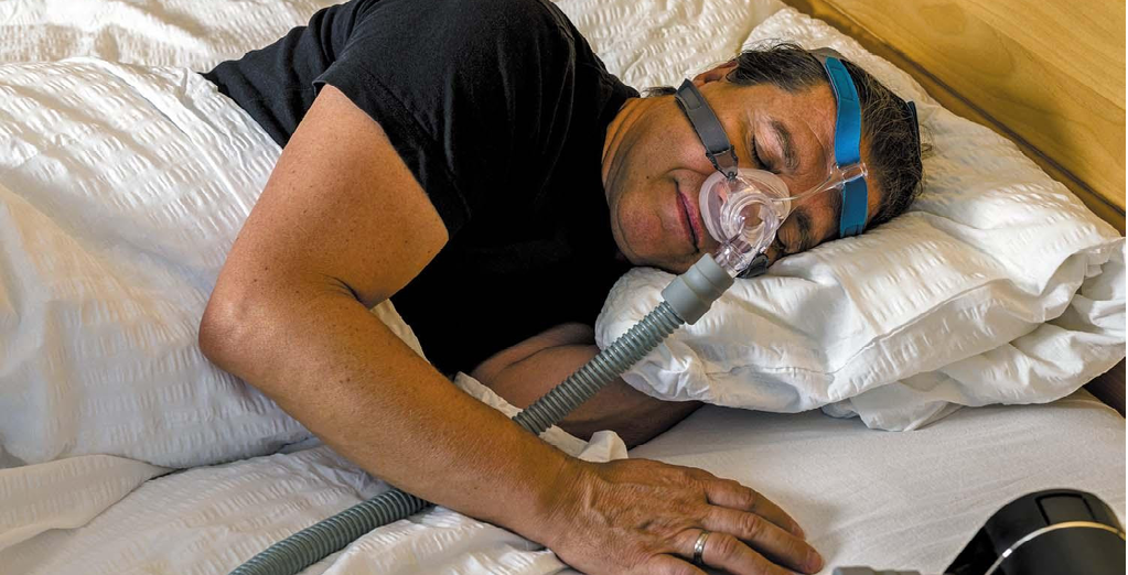 A man is sleeping on a bed with a mask on his face. AI generated content