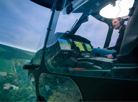 A man is sitting in a helicopter cockpit, looking out at the landscape. AI generated content