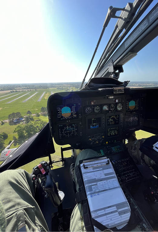 A person is sitting in a helicopter cockpit with a view of the ground below. AI generated content