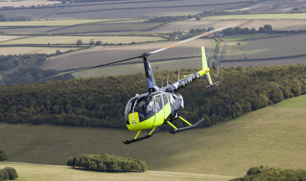 A yellow helicopter is flying over a grassy field. AI generated content