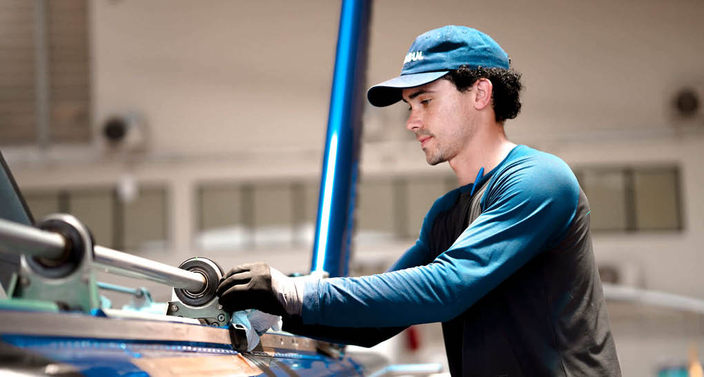 A man wearing a blue cap and blue shirt is working on a machine. AI generated content