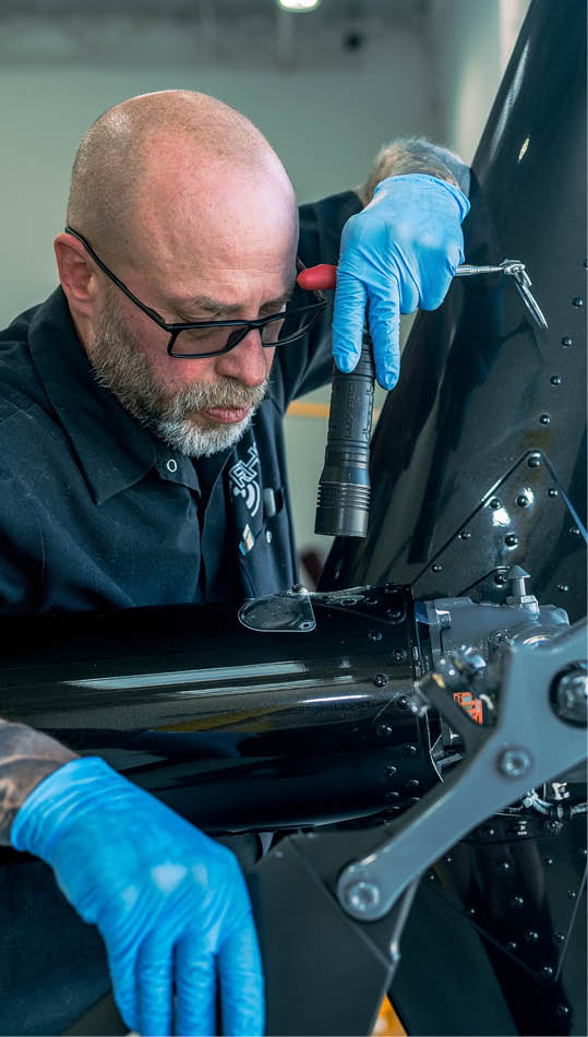 A man wearing blue gloves is working on a helicopter. AI generated content