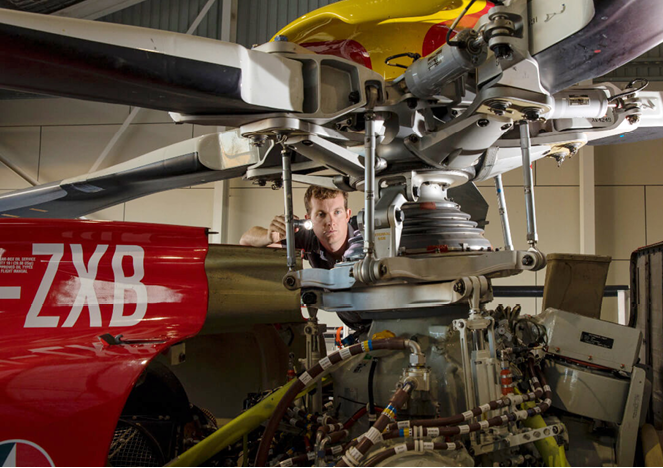 A man is working on a helicopter in a hangar. AI generated content