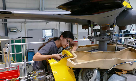 A woman is working on the engine of a plane in a hangar. AI generated content