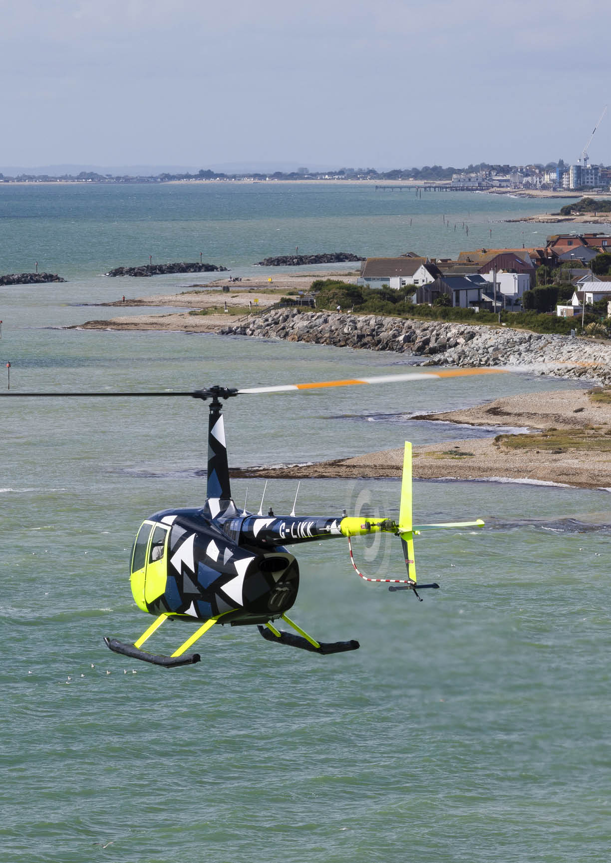 A yellow helicopter is flying over a body of water. AI generated content