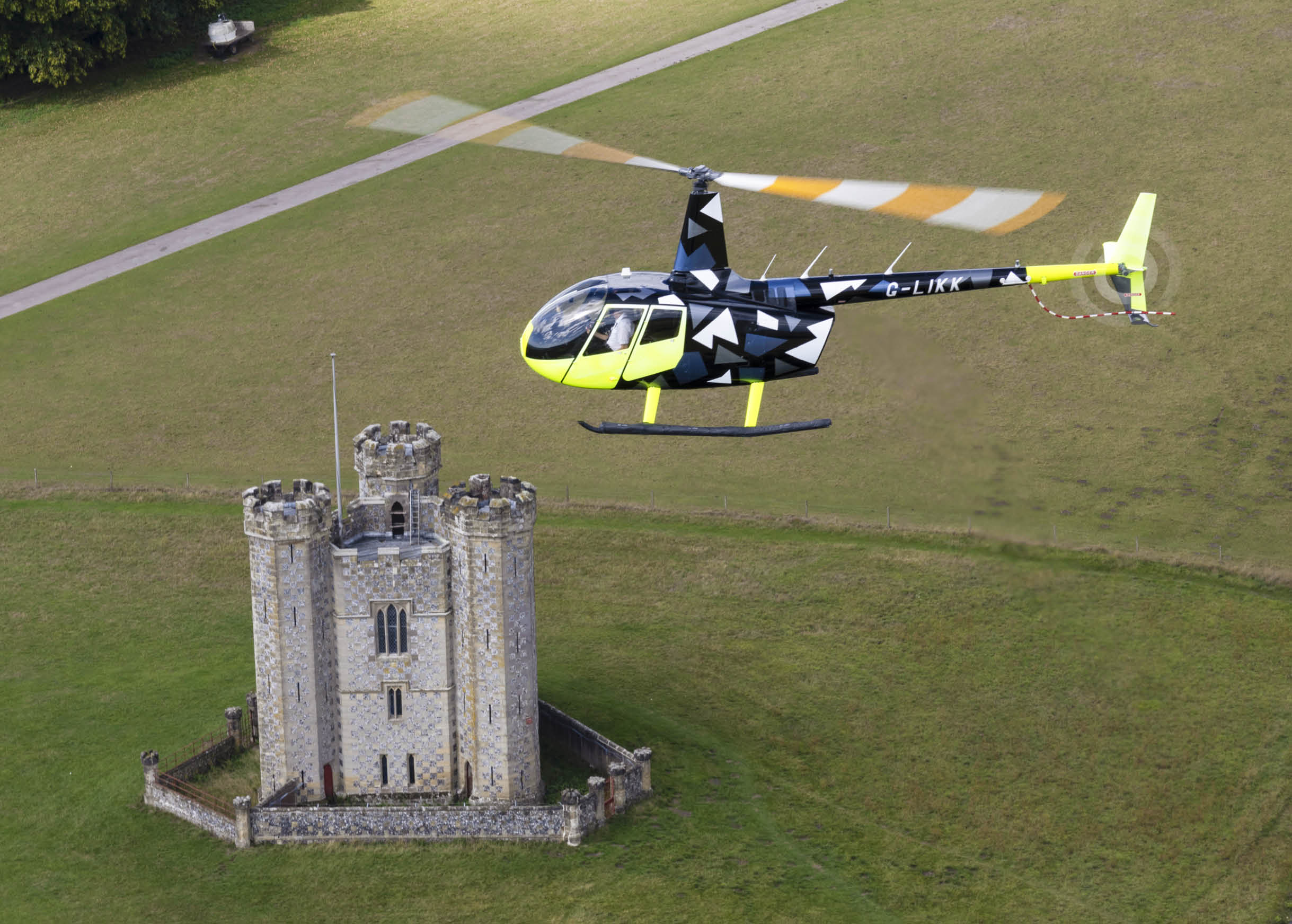 A yellow and black helicopter is flying over a castle. AI generated content