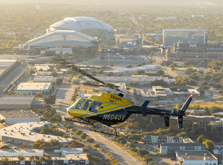 A yellow helicopter is flying over a city with a large stadium in the background. AI generated content
