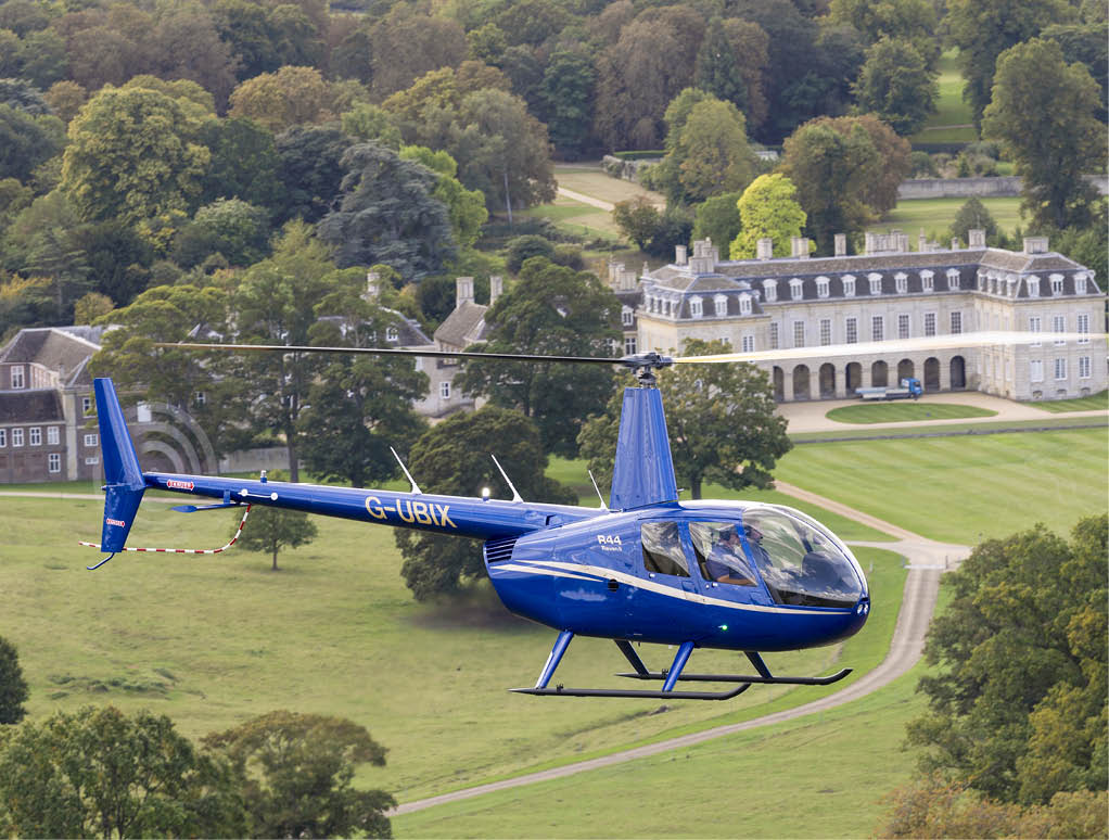 A blue helicopter is flying over a large mansion with a green lawn. AI generated content