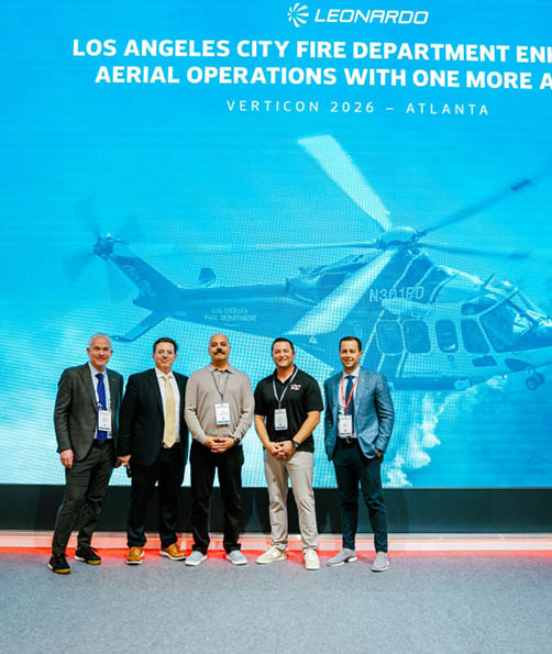 Four men pose in front of a large screen with a helicopter on it. They are wearing suits and ties. AI generated content