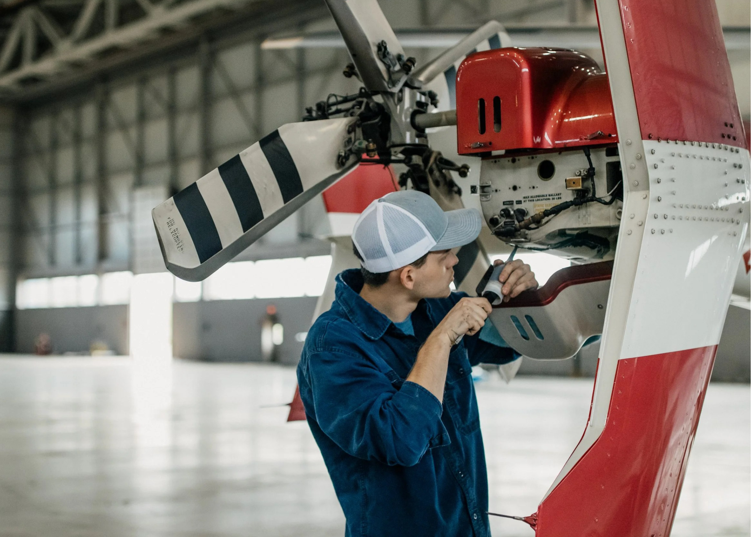 A man wearing a blue shirt is working on a helicopter. AI generated content