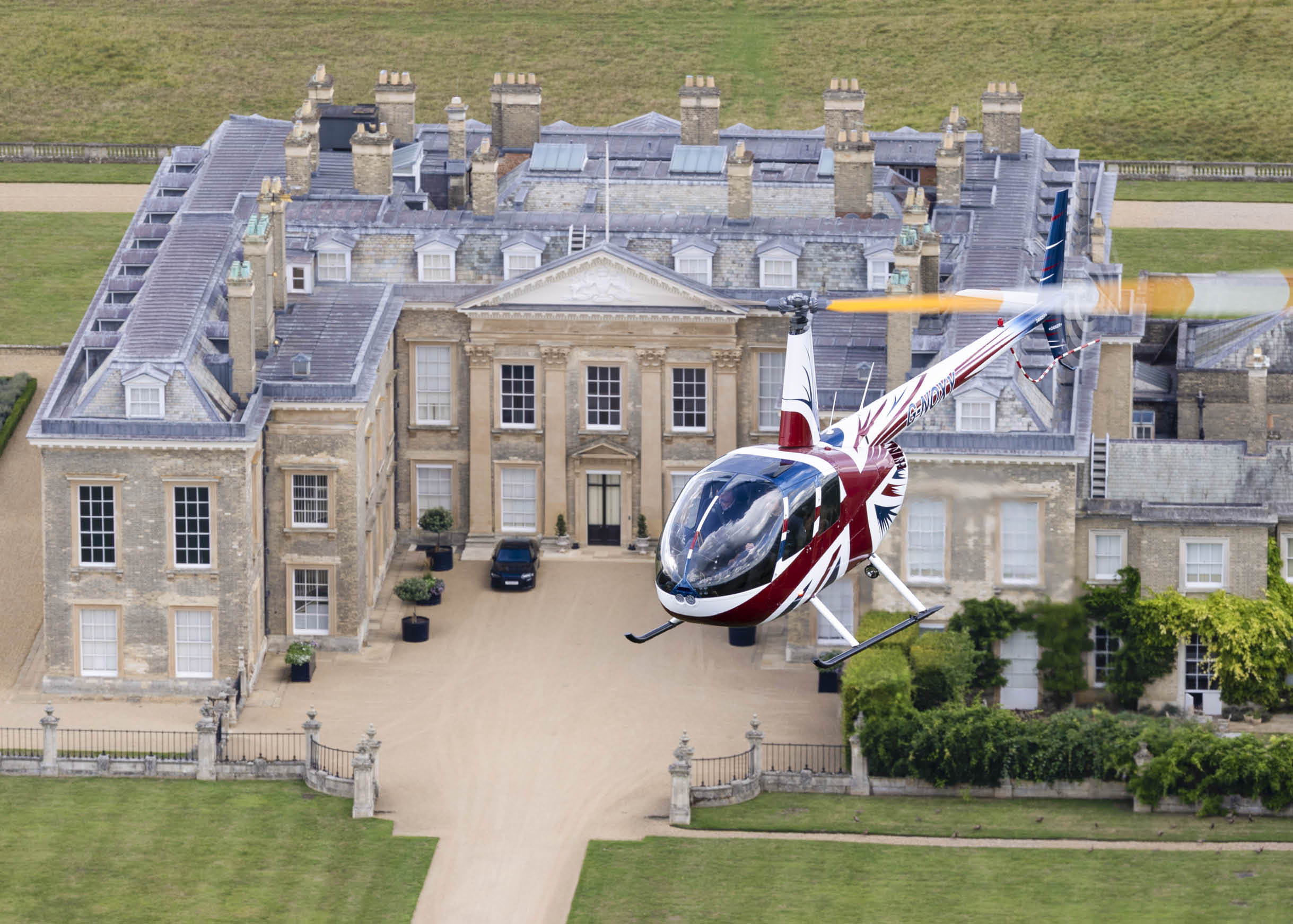 A red and white helicopter is parked in front of a large house. AI generated content
