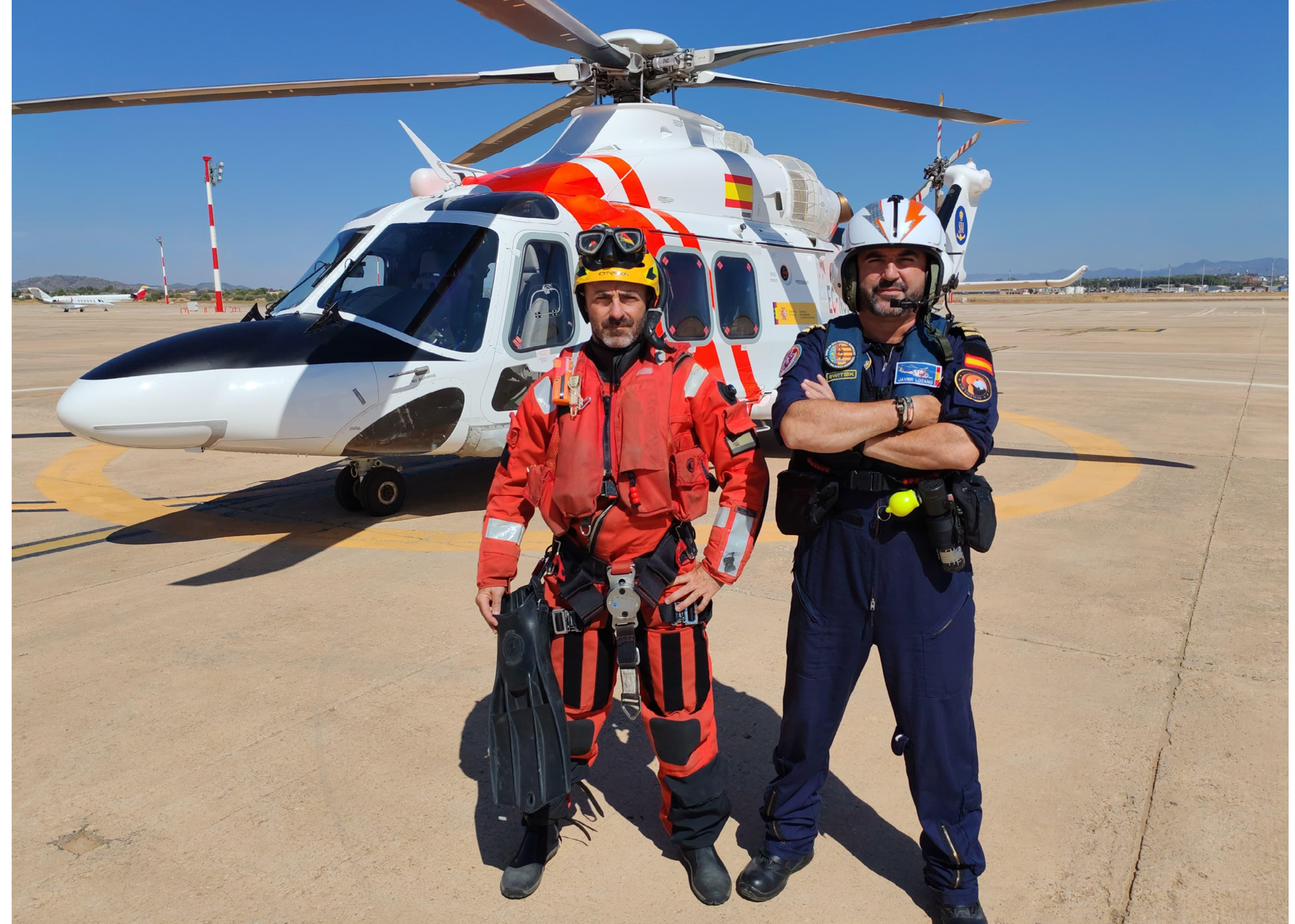 Two men standing in front of a helicopter. Description generated by AI