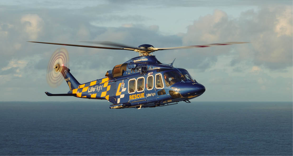 A blue and yellow helicopter flying over the ocean. Description generated by AI