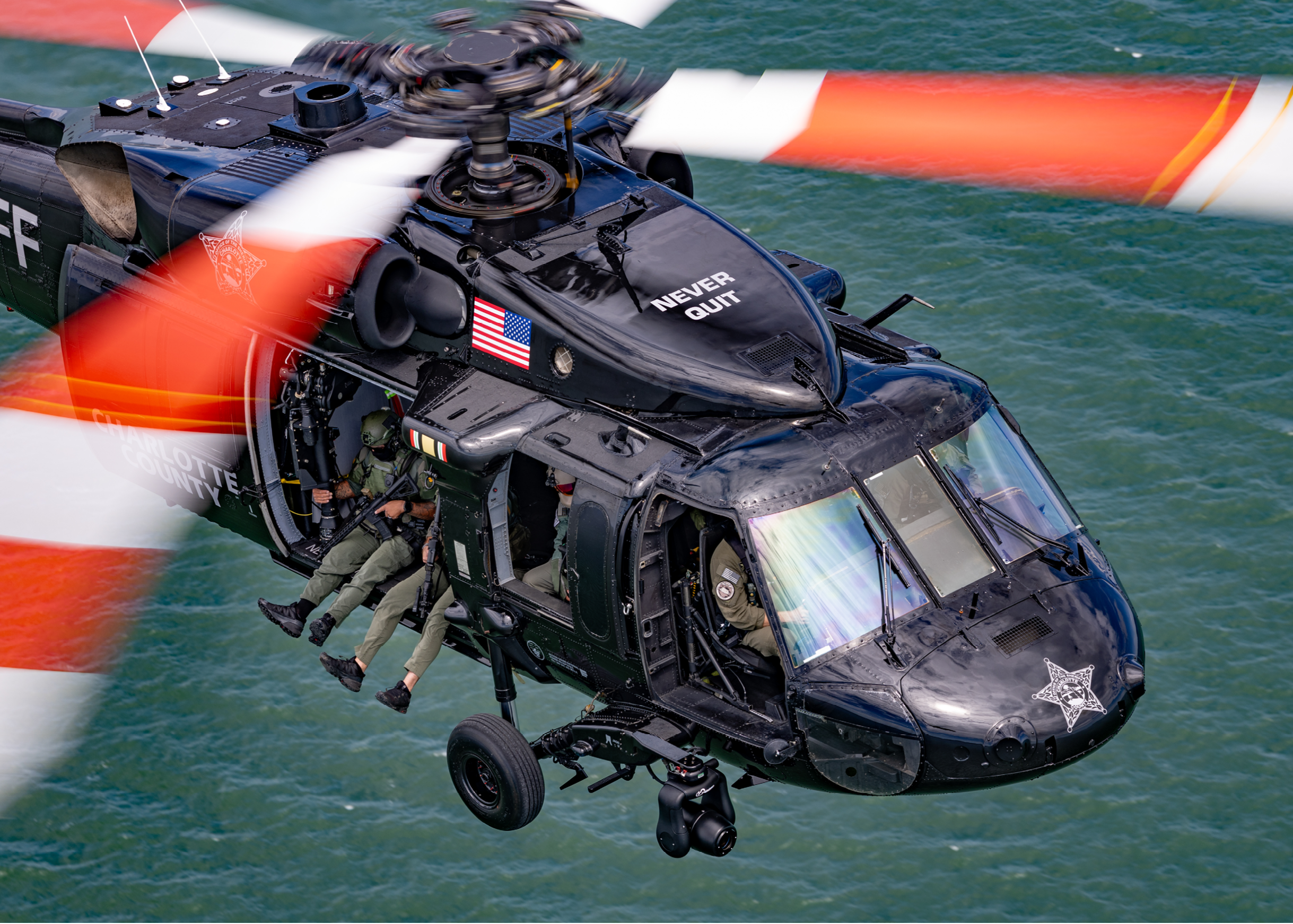 A black helicopter with a red and white tail. Description generated by AI