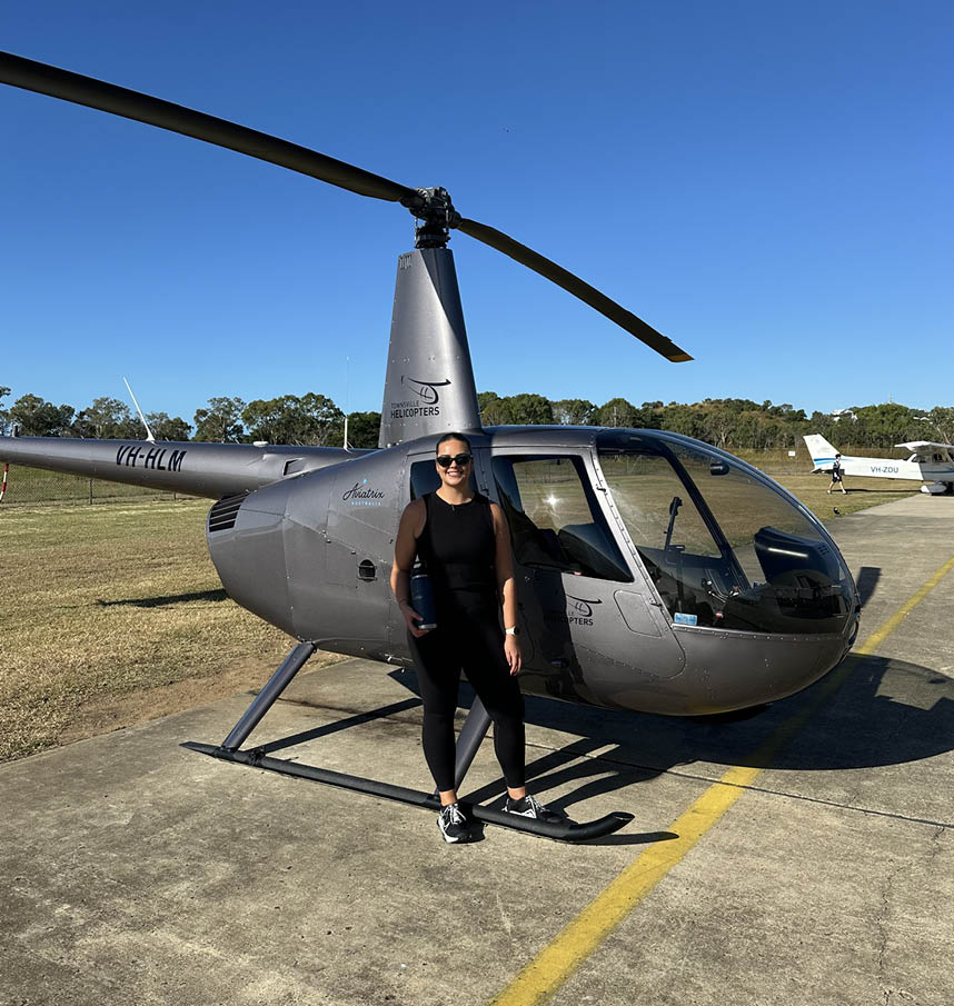 A man standing in front of a helicopter. Description generated by AI