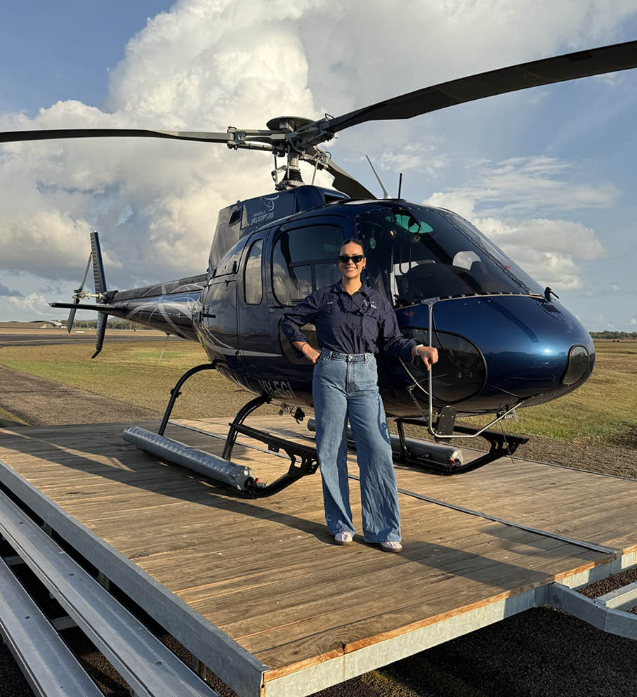 A man standing in front of a helicopter. Description generated by AI