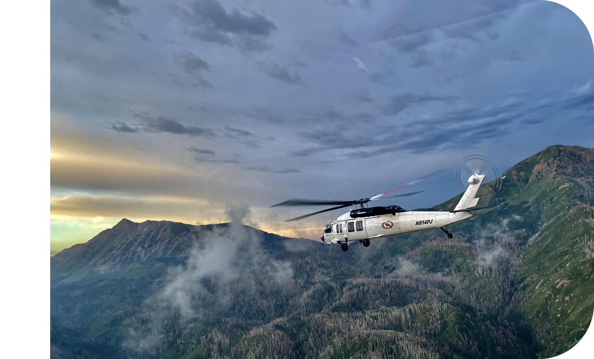 A helicopter flying over a mountain range. Description generated by AI