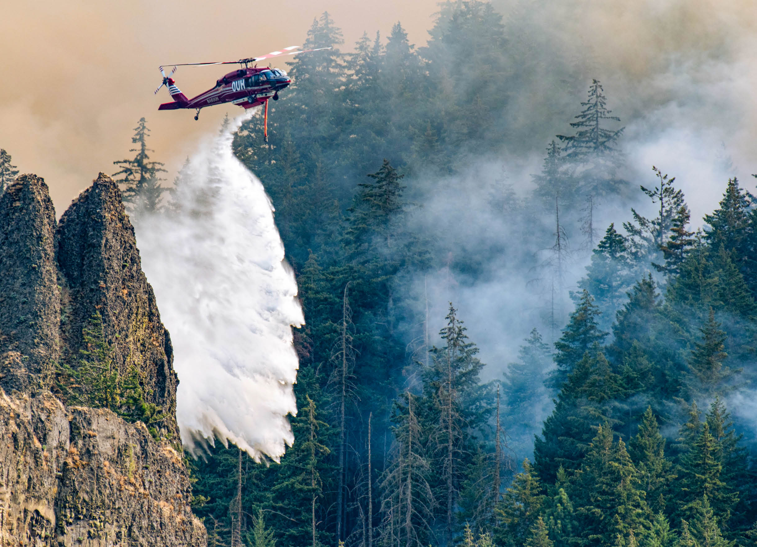 A helicopter is flying over a forest with a fire. Description generated by AI