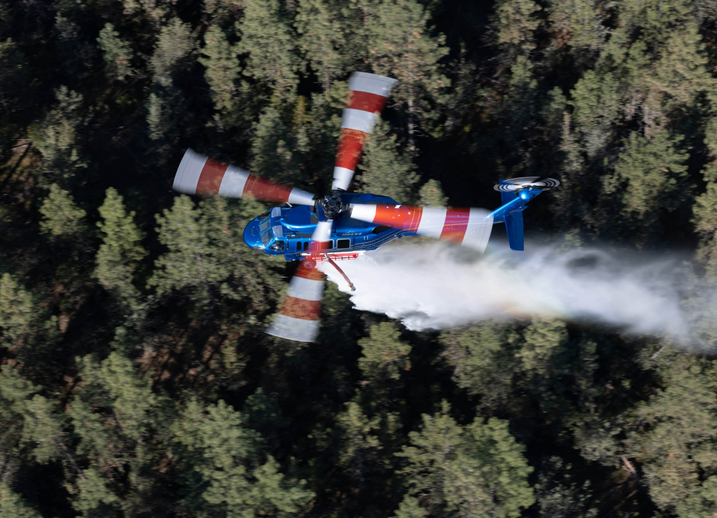 A blue and red helicopter flying through the air. Description generated by AI